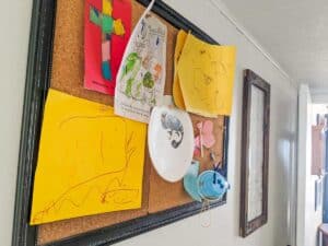 childrens artwork organized on framed cork board