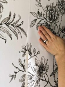 smoothing a peel and stick wallpaper panel onto mobile home bathroom wall