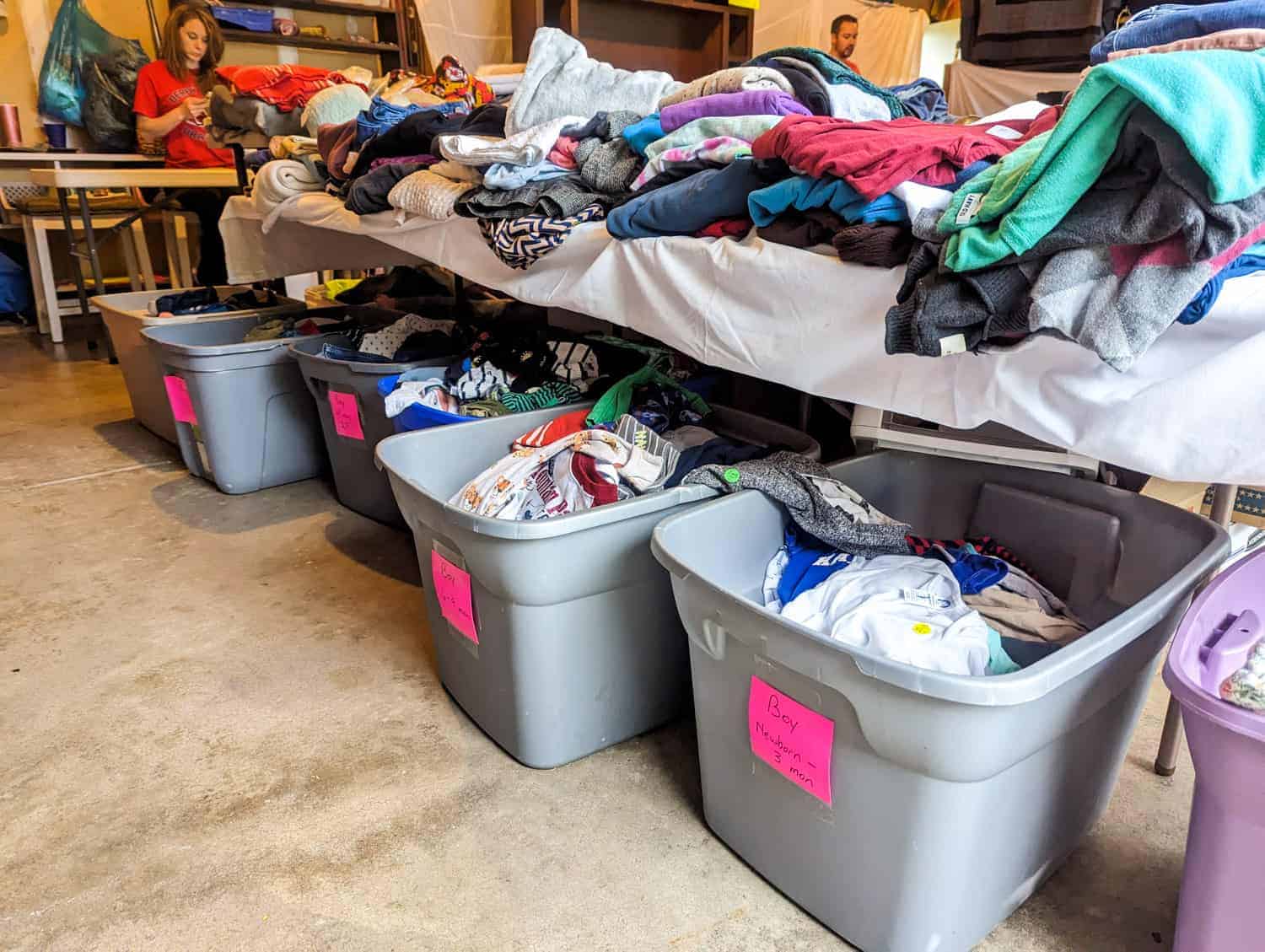 clothes organized on tables and in tubs for a garage sale