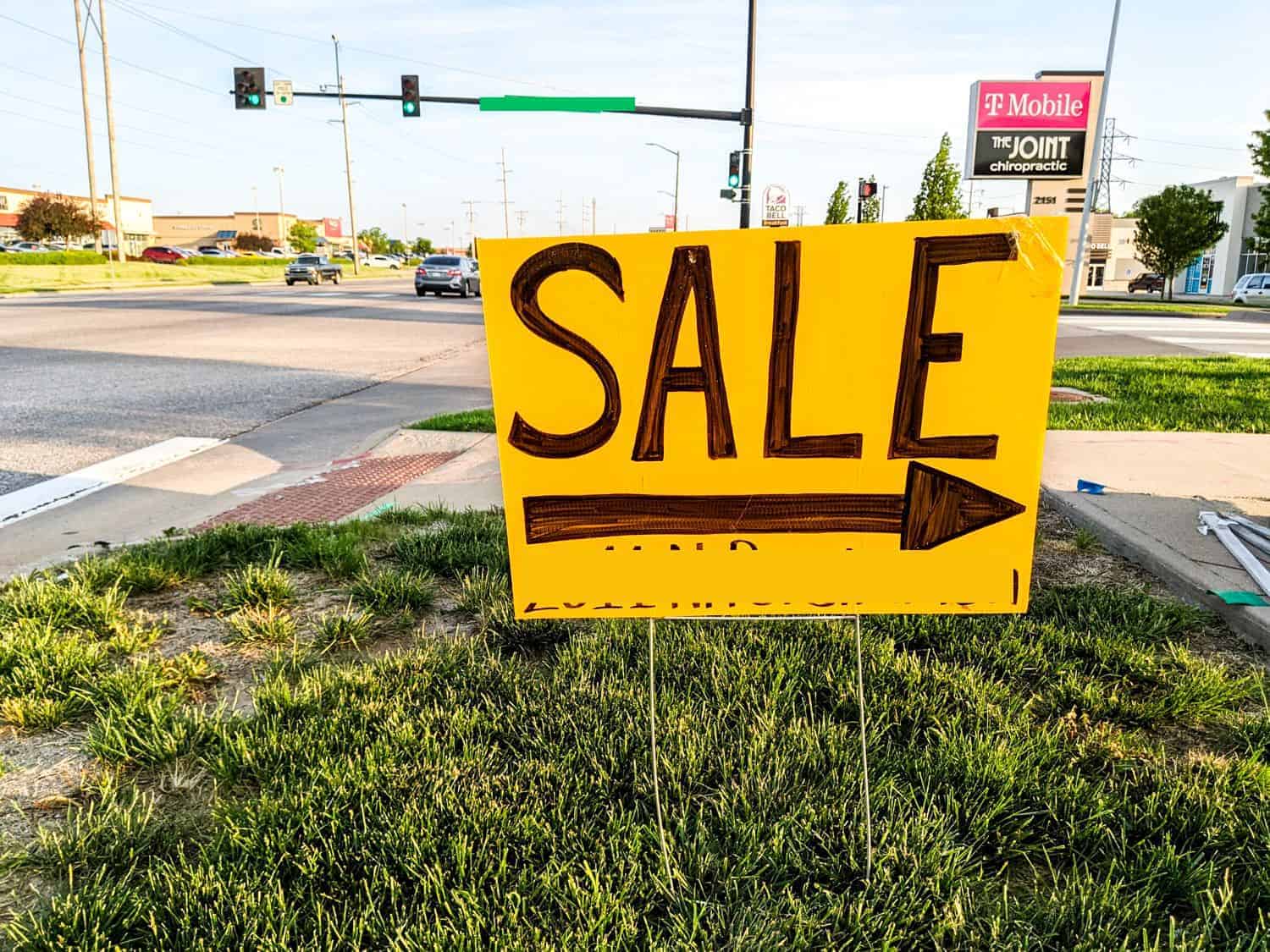 yellow sale sign displayed in grassy area