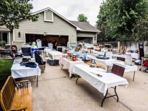 residential driveway filled with tables of items in a garage sale