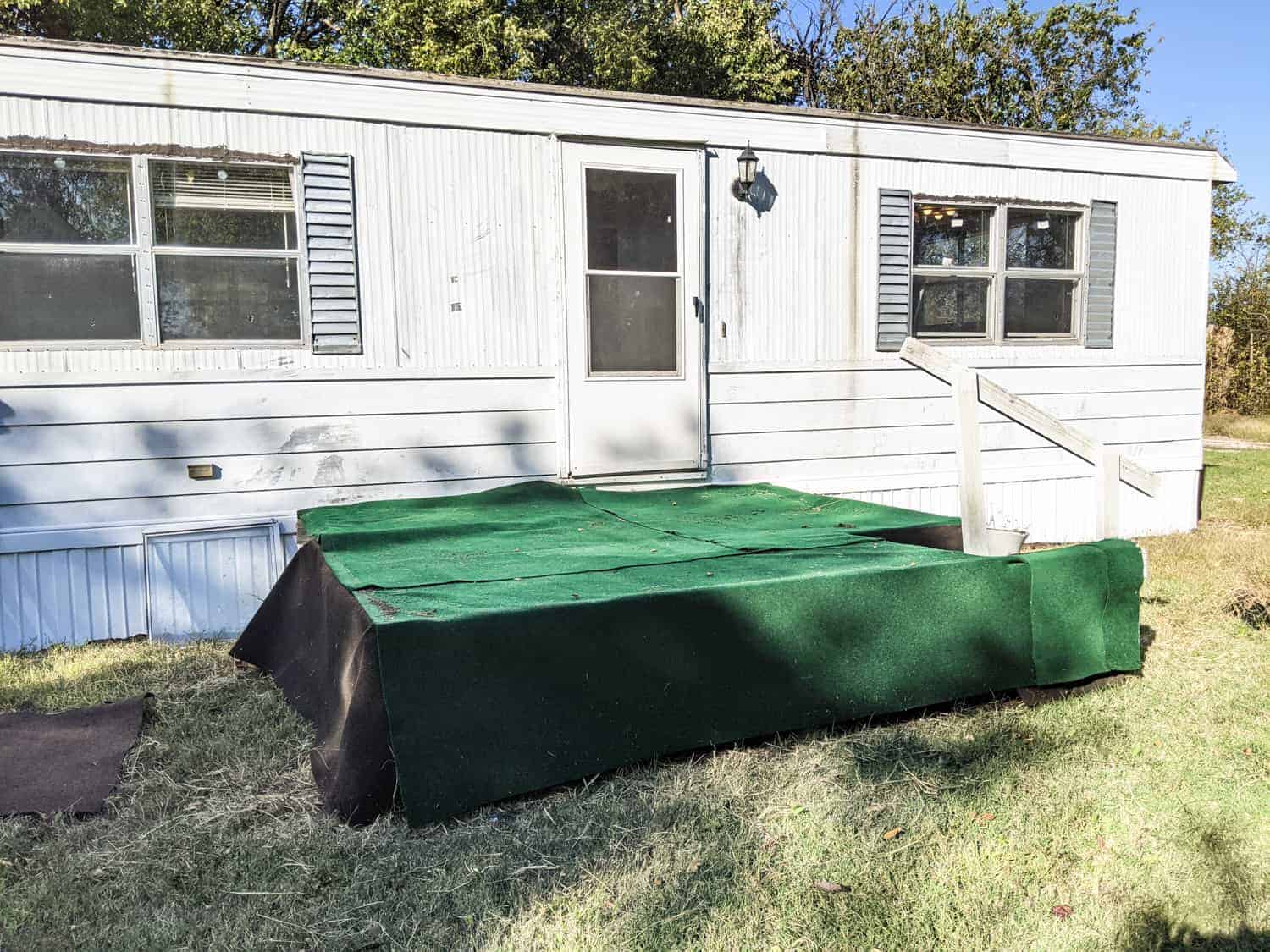 exterior of older mobile home with white siding