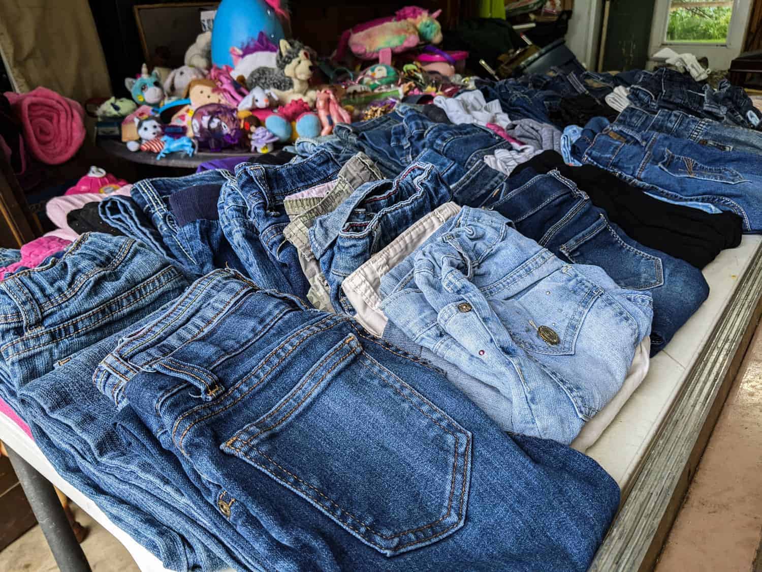 table full of folded jeans for sale at a garage sale