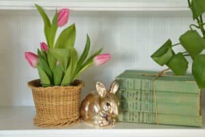 white bookshelf decorated with vintage budget friendly easter decor flowers bunny figurine and books