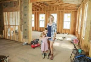 mother and young children stand in the midst of a home addition during its construction